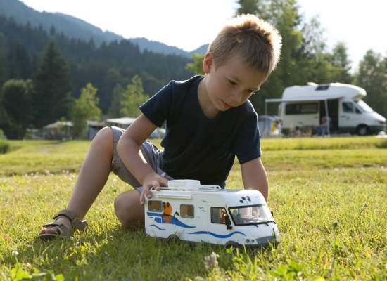 Boy playing with toy RV in front of family RV